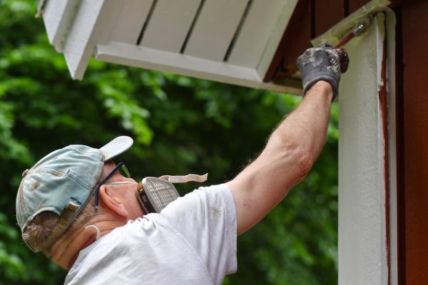 A man painting house exterior with white color A man painting house exterior with white color