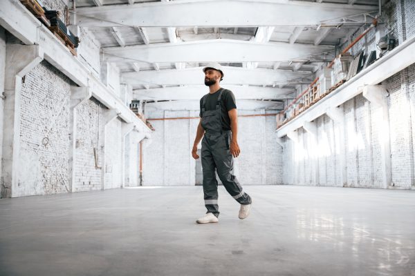 Painted in white. Male worker is in the empty warehouse Painted in white. Male worker is in the empty warehouse